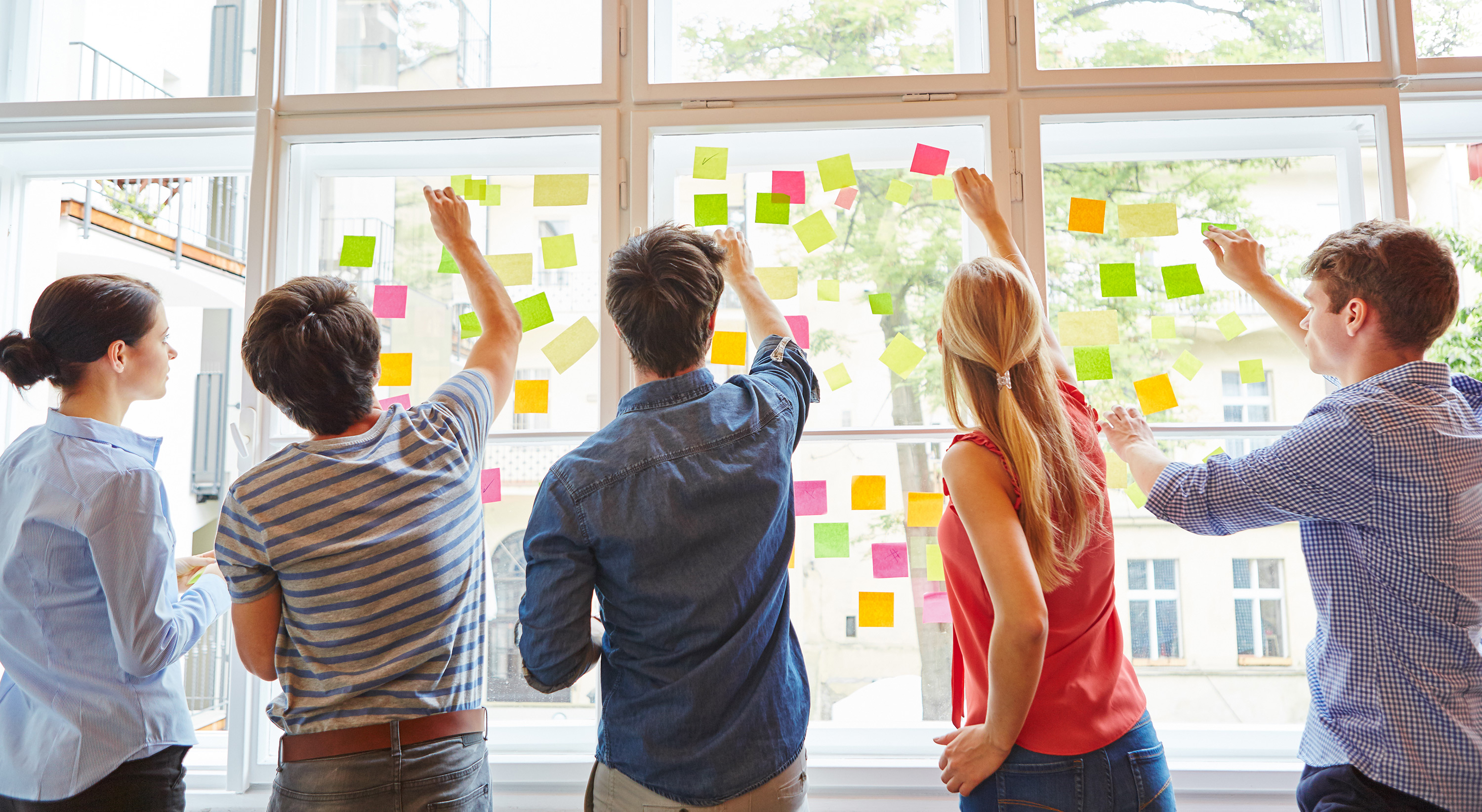 Studierende kleben Post-it-Notizen auf Fensterscheibe