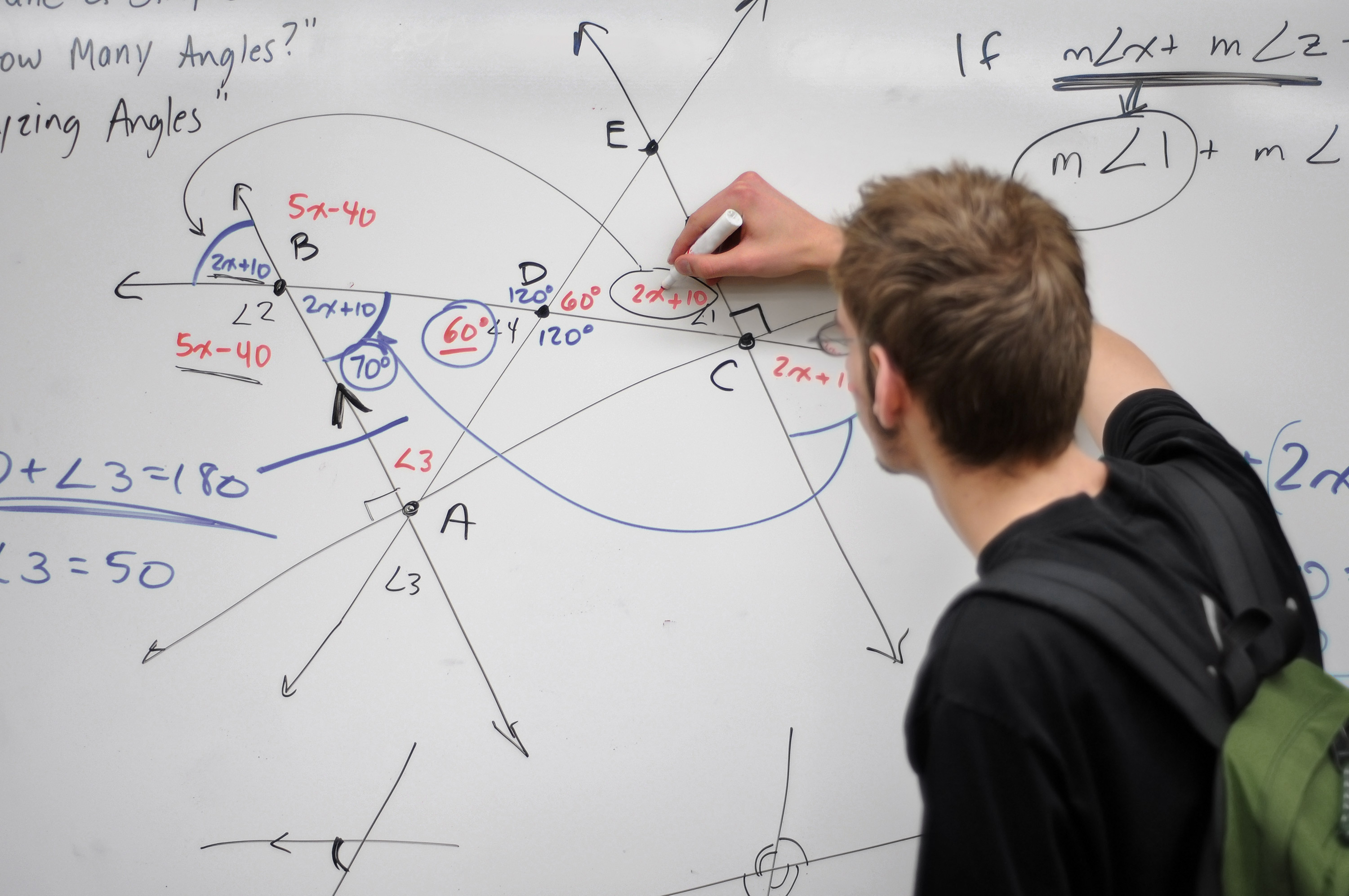 Junger Mann zeichnet auf einem Whiteboard