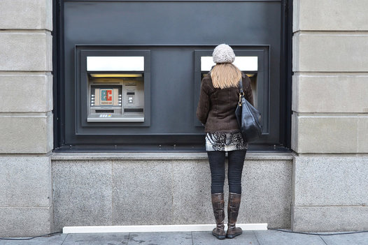 Junge Frau holt Geld am Geldautomaten